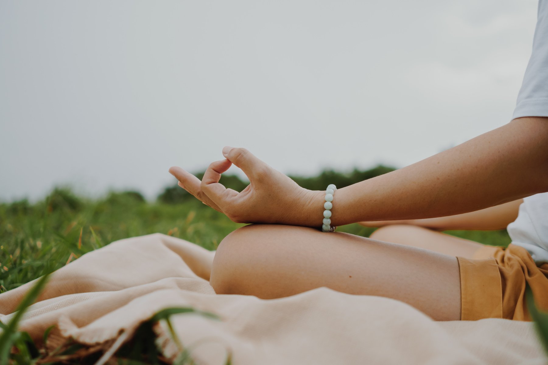 Woman practicing yoga lesson, breathing, meditating exercise, outdoor in grass field. Well being, wellness concept